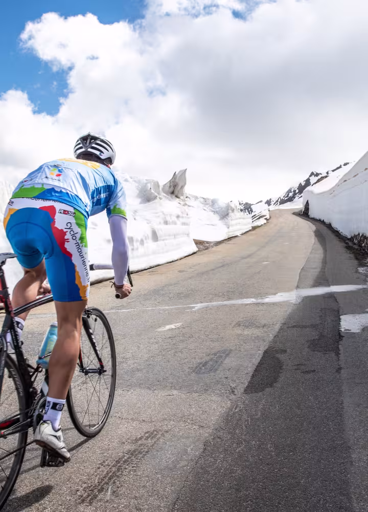 Fietser in de sneeuw op de Route des Grandes Alpes