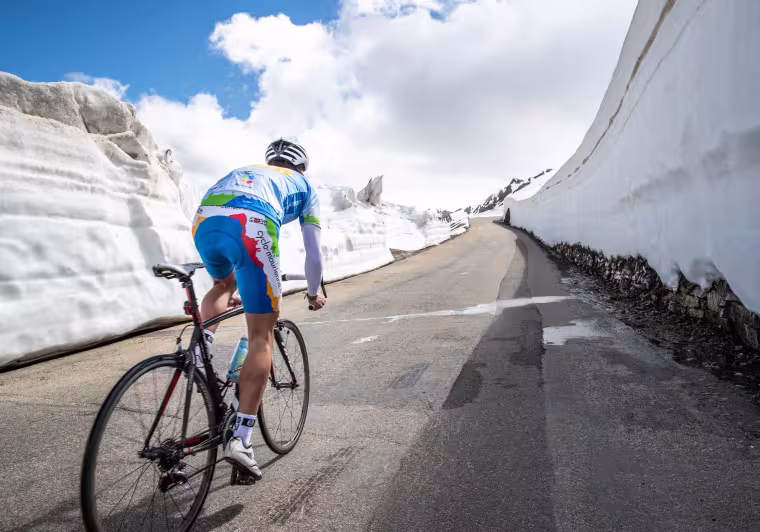 Fietser in de sneeuw op de Route des Grandes Alpes