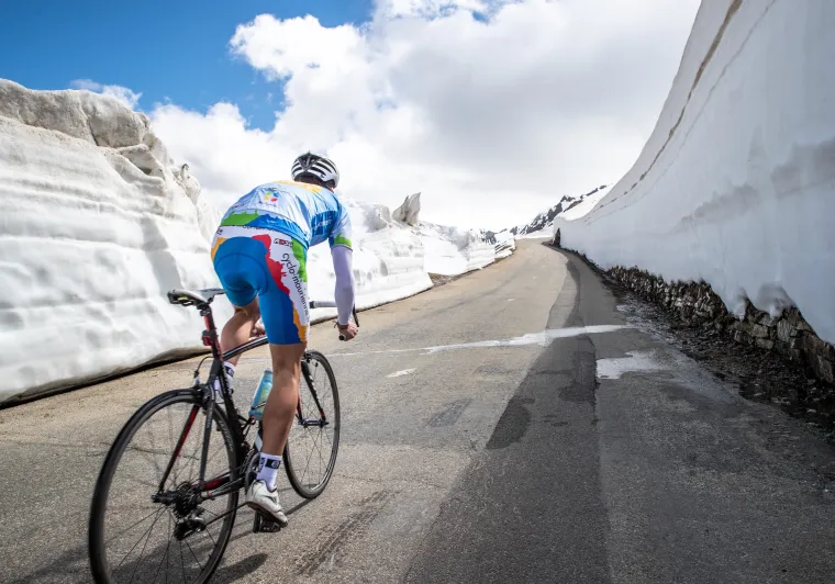 Fietser in de sneeuw op de Route des Grandes Alpes
